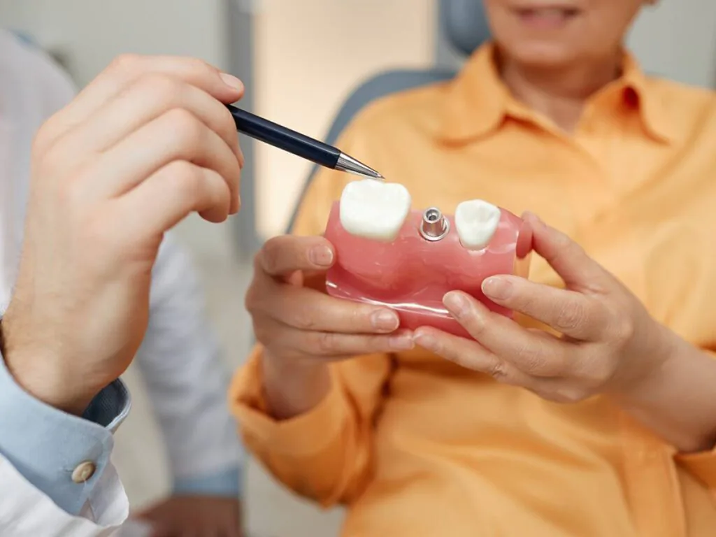 Dentist showing patient a dental implant model